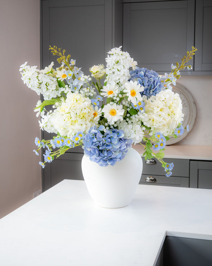 White vase with a bouquet of flowers on a kitchen counter